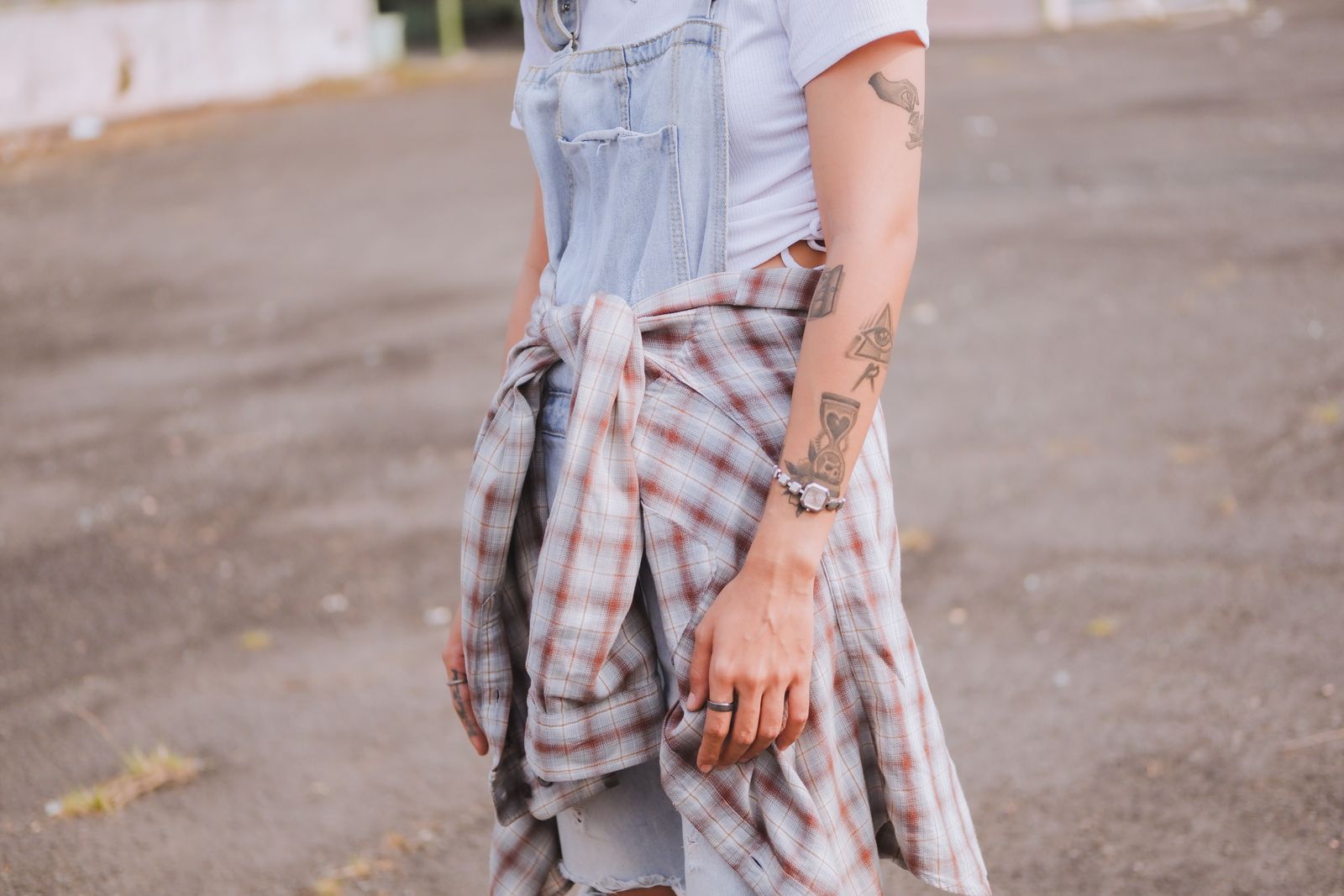 Close-up of a person in a denim jumper with tattoos, showcasing casual fashion style.