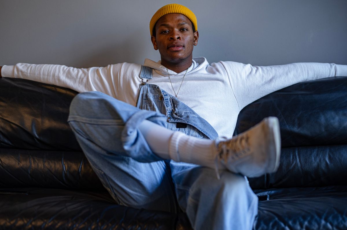 Young man in denim and hoodie lounging on a sofa. Stylish urban casual wear.