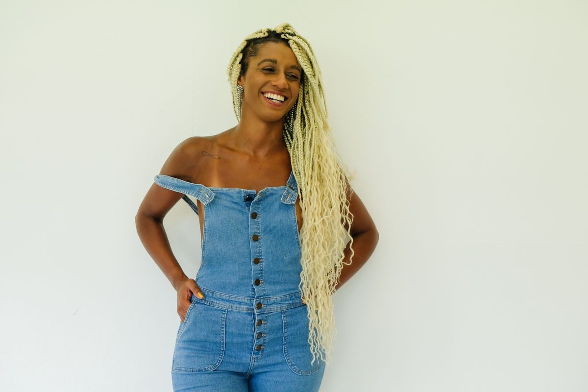 Portrait of a joyful woman in denim overalls on a white background.