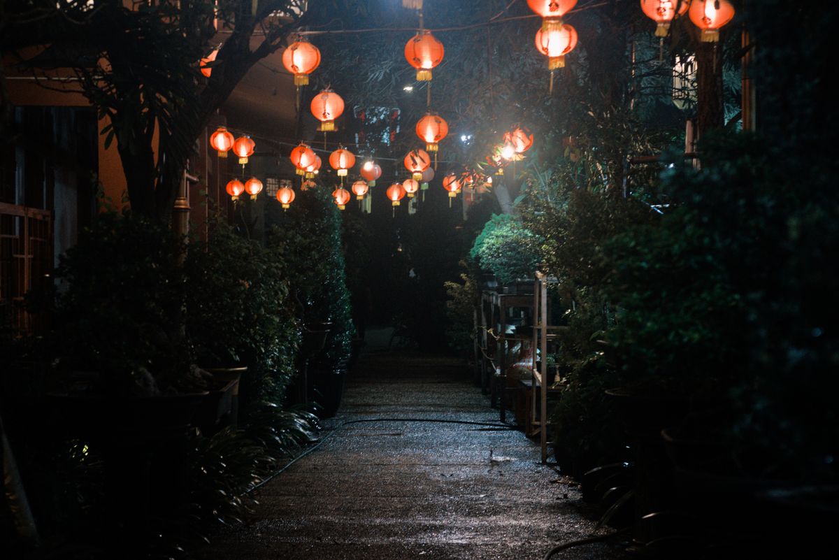 Beautiful night scene of a garden path lit by traditional red lanterns in Indonesia.