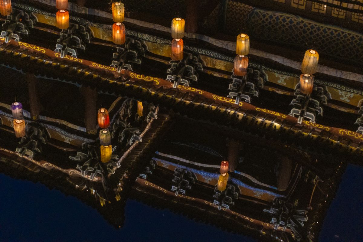 Traditional lanterns reflected vividly in water at night.
