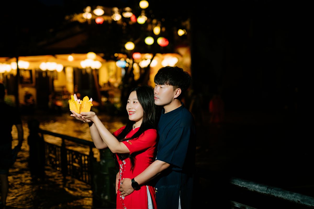 Couple enjoying a traditional lantern ceremony by the water at night.