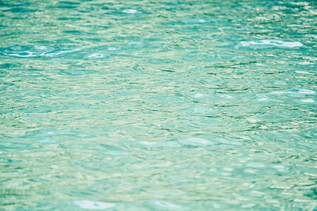 Illustration of still rippling turquoise water with light reflections and gentle waves.