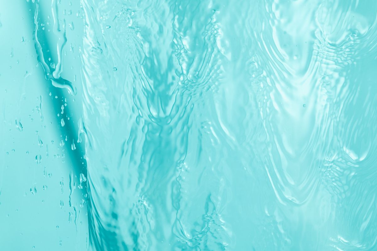 Abstract close-up of turquoise water ripples with light reflections and wave patterns.