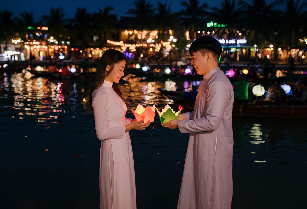 Couple releasing lanterns on the water at Hội An Lantern Festival in Vietnam.