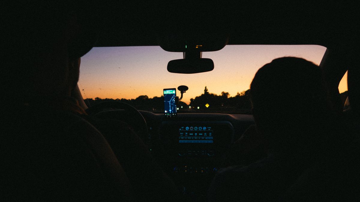 Interior view of a car with navigation app at sunset, highlighting travel and technology.