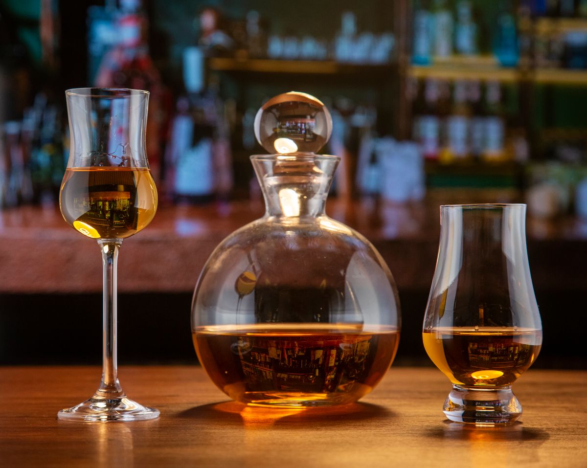 Close-up of elegant glassware with amber liquor set on a wooden bar counter.