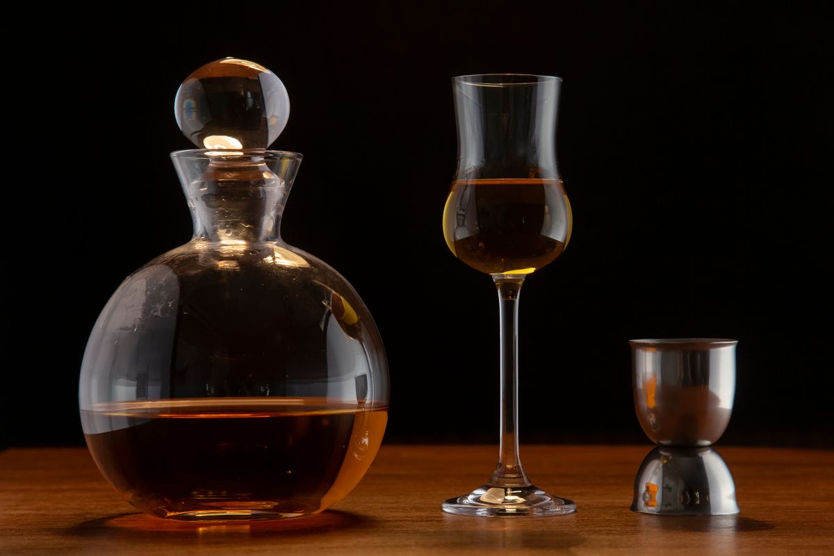 Elegant still life with a whiskey decanter, glass, and jigger on wooden surface.