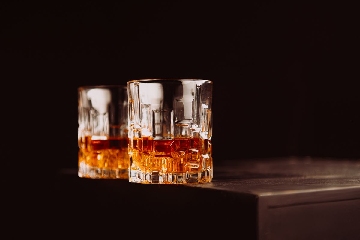 Two whiskey glasses with amber liquid on a dark surface, creating a cozy atmosphere.