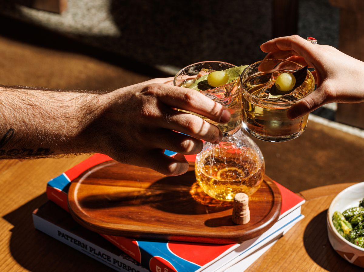 Close-up of two adults toasting with whiskey glasses in a warm, celebratory setting.