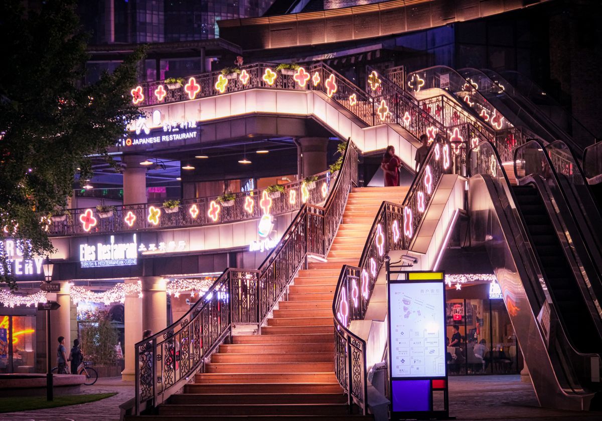 Colorful illuminated staircase in a lively Shanghai outdoor setting at night.