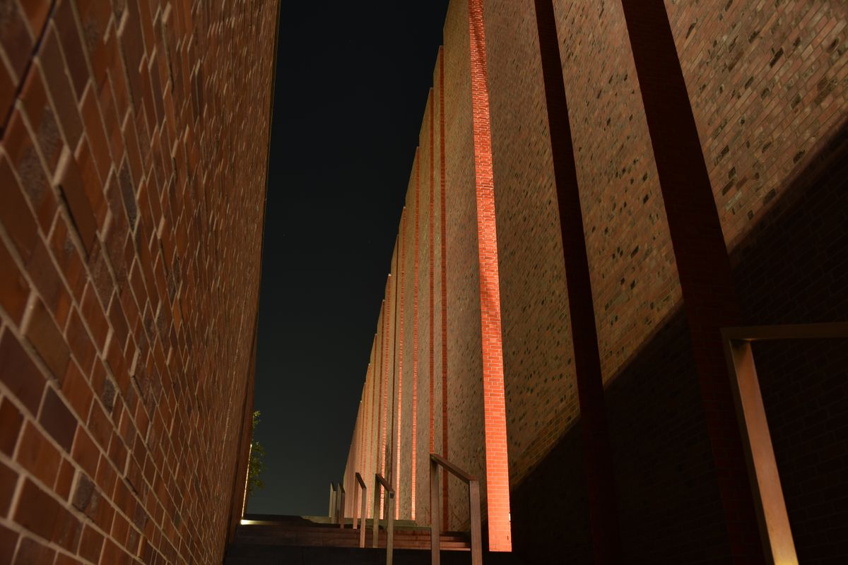 Night view of urban brick walls featuring stairs and dramatic lighting.