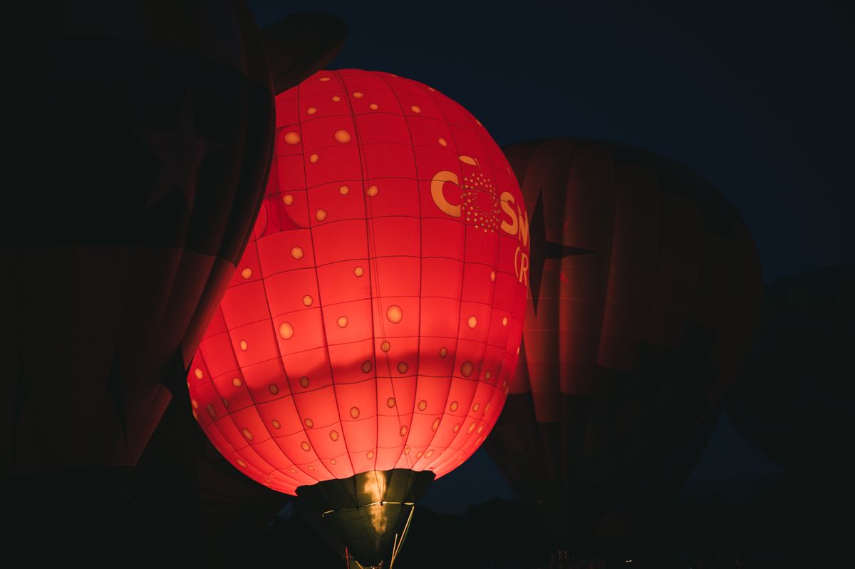 Glowing red hot air balloons create a stunning night spectacle at an outdoor festival.