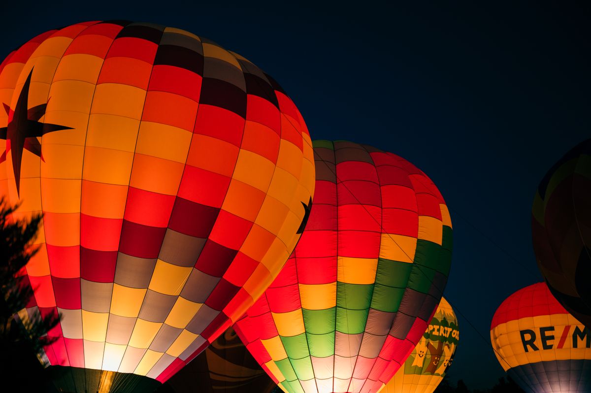 Illuminated hot air balloons glowing vividly against the night sky, showcasing bright colors and adventure.