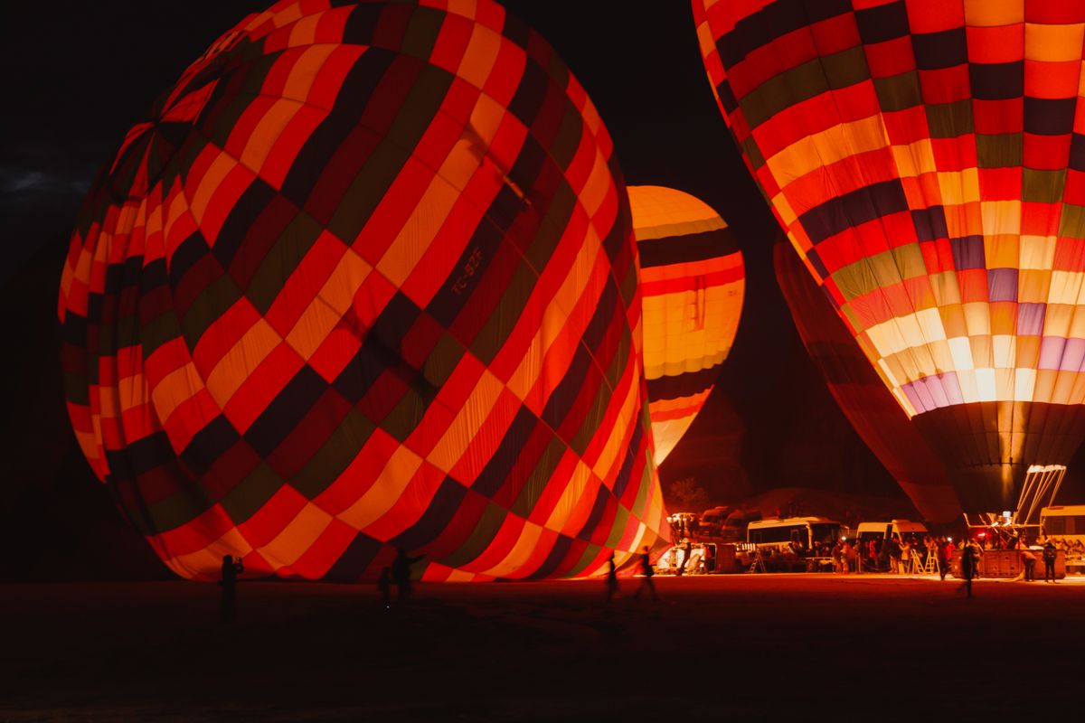 Colorful hot air balloons illuminated at night, ready for ascension during a festival.