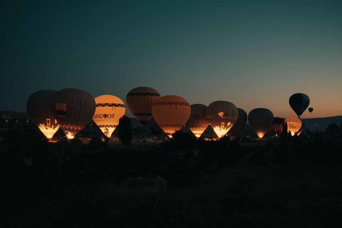 Hot air balloons illuminated against a dark night sky during a vibrant outdoor festival.