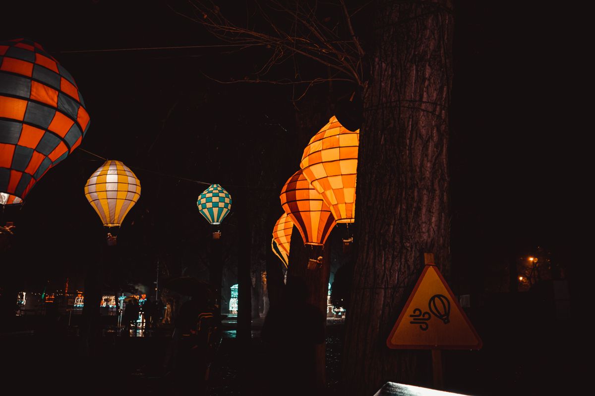 Vibrant illuminated hot air balloons light up a dark festival night scene outdoors.