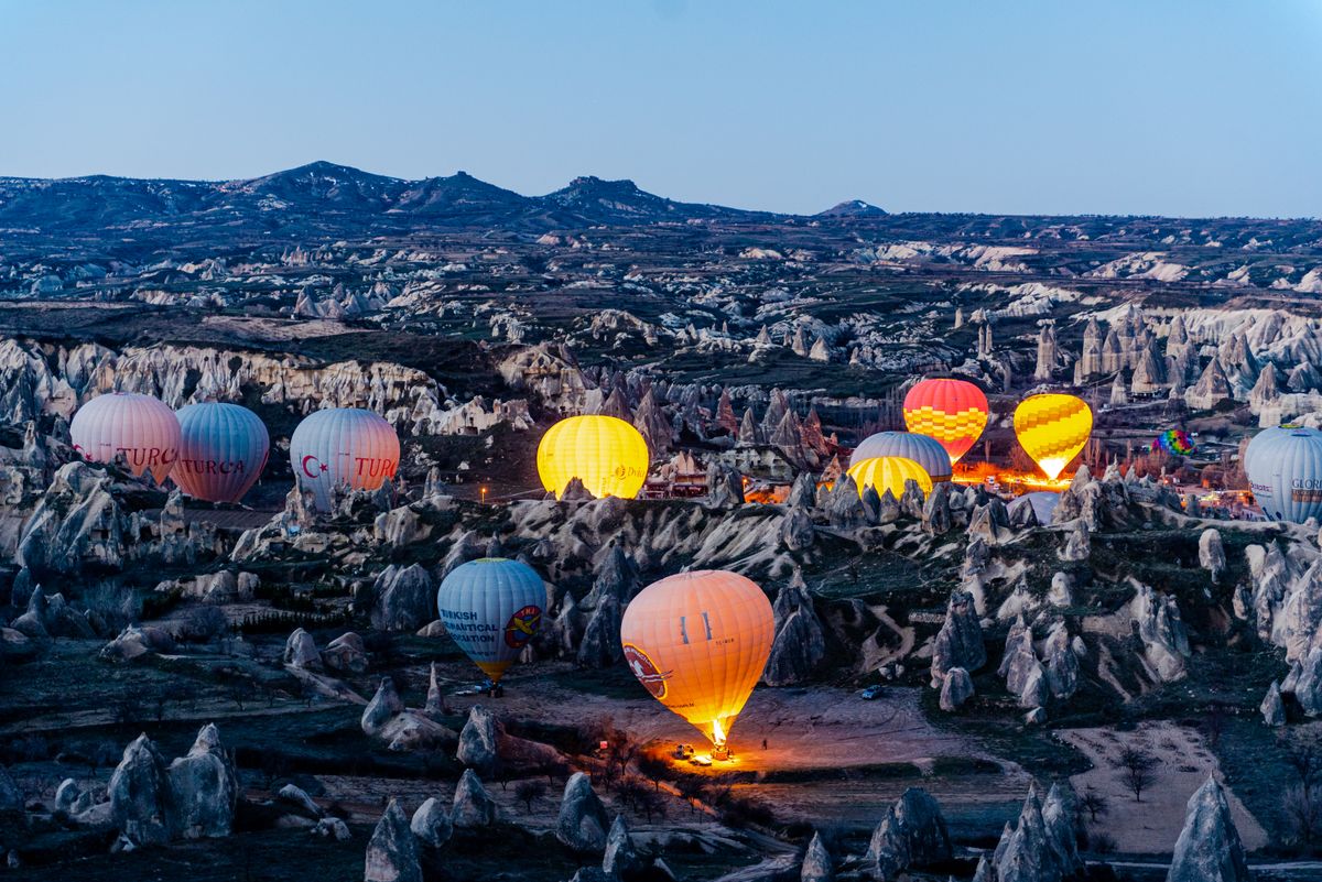 Colorful hot air balloons lighting up the Cappadocia landscape at twilight, ready for an adventure.