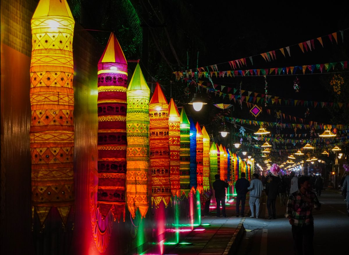 A lively festival scene with vibrant lanterns and decorations illuminated at night, creating a festive atmosphere.