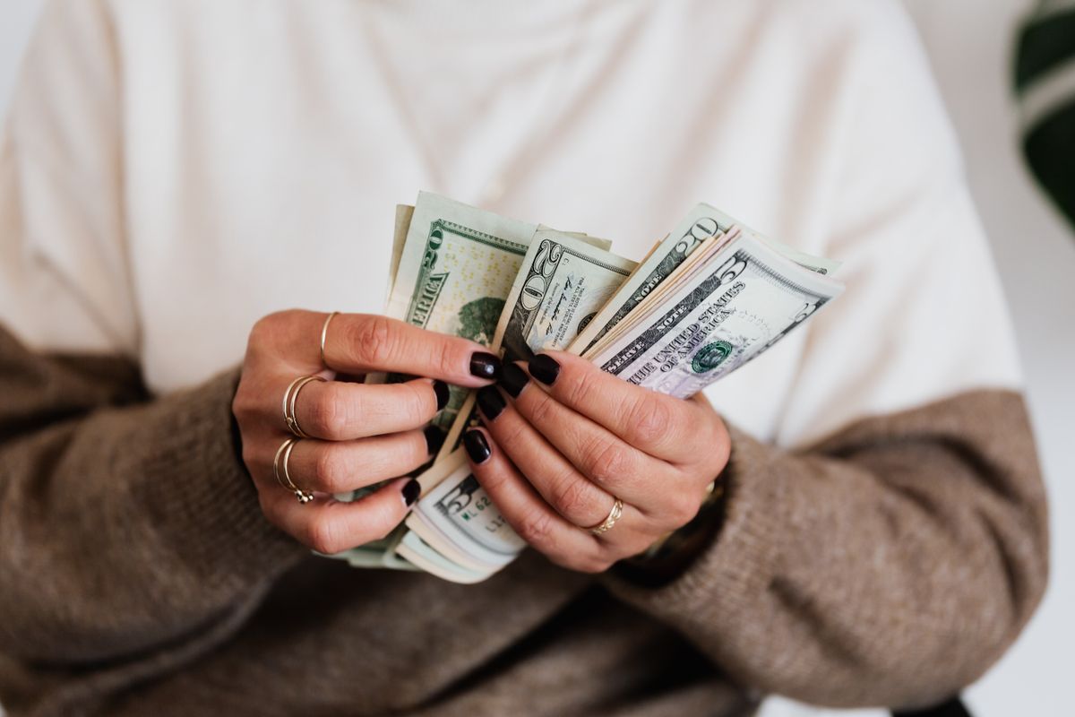 Hands holding and counting US dollar bills, highlighting finance and cash flow.