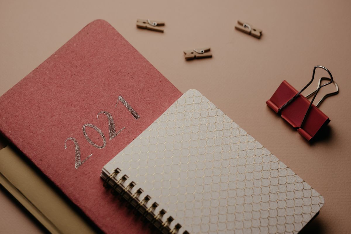 Close-up of 2021 notebook, binder clip, and paper clips on a neutral background.