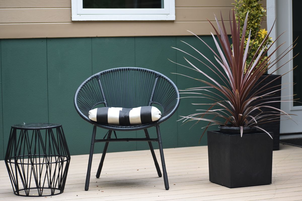 Modern outdoor patio scene with a distinctive chair, side table, and potted plant.