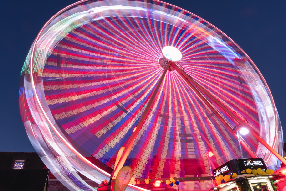 Vibrant Ferris wheel at a night fair in Geldern, Germany, showcasing colorful light patterns.