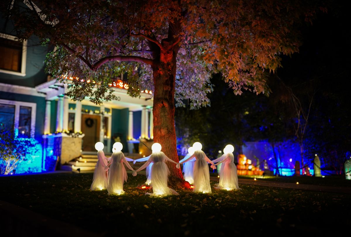 Spooky illuminated Halloween decorations of ghosts in a yard at night in Redlands, CA.