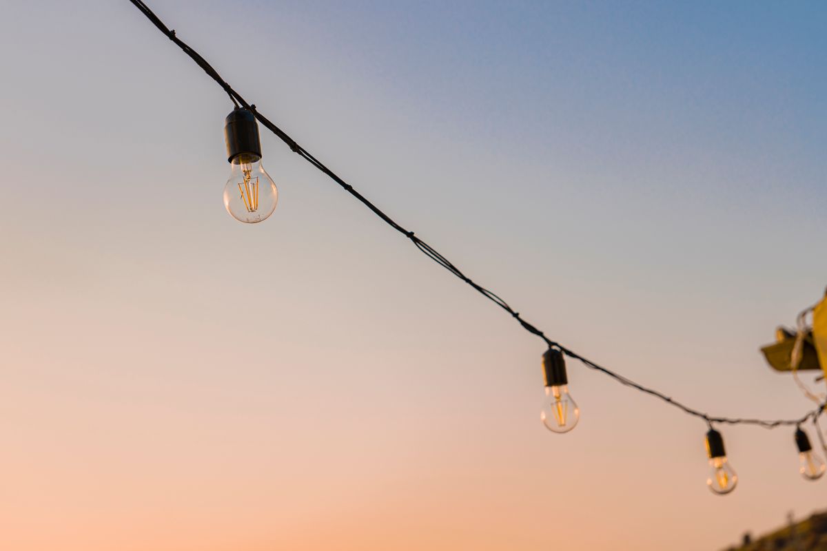 Beautiful string lights hanging against a colorful Sicilia sunset sky, capturing a serene outdoor ambiance.