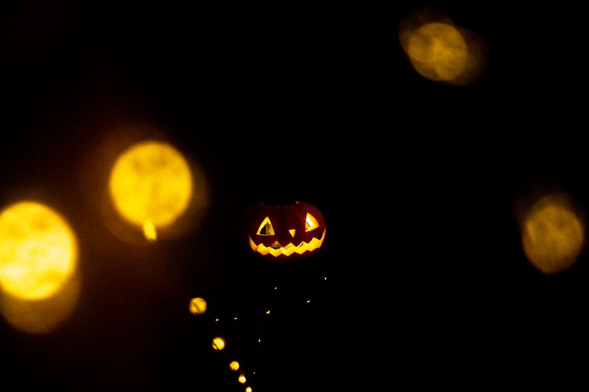 Spooky jack o' lantern illuminated in darkness with bokeh lights, perfect for Halloween imagery.