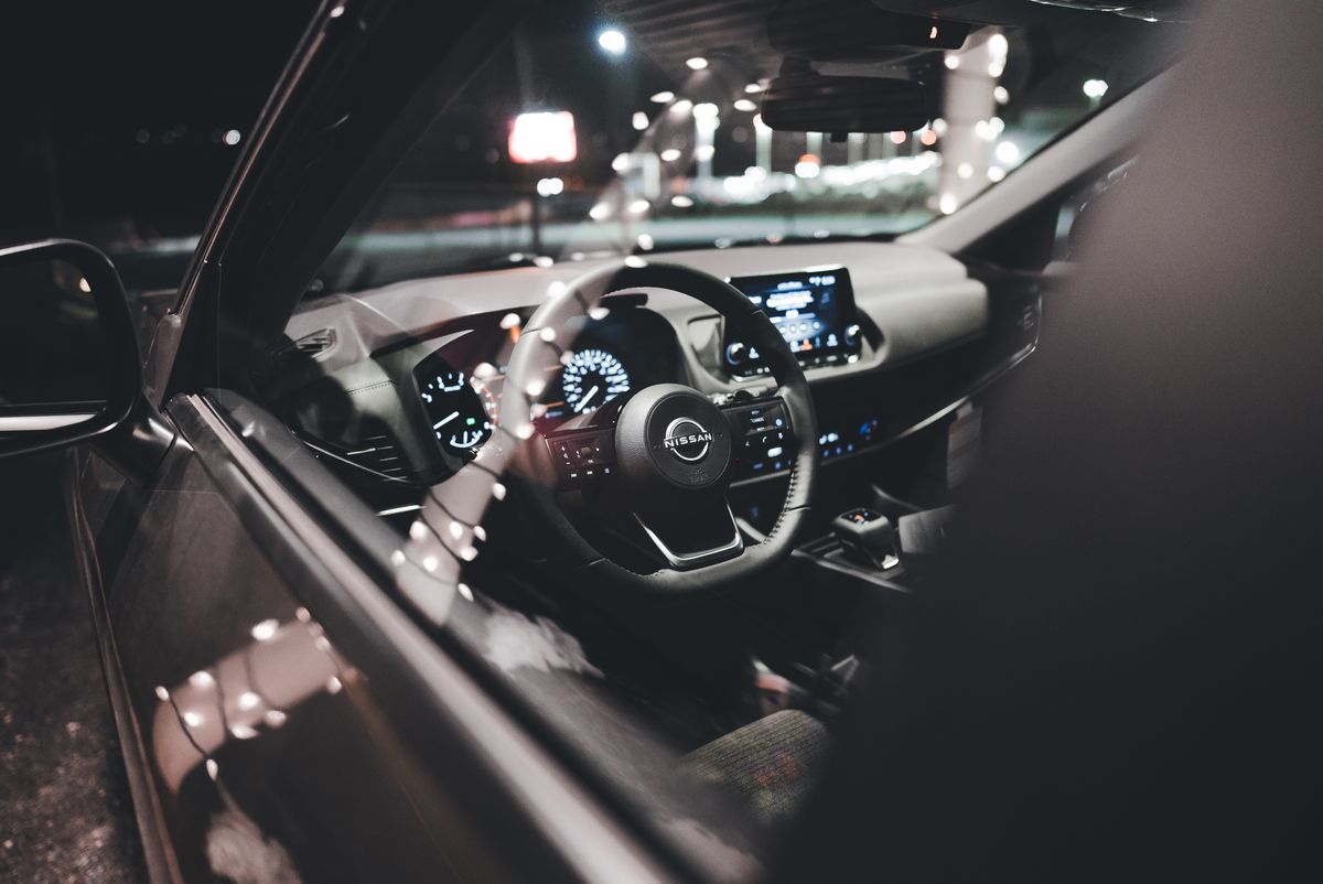 Close-up of a Nissan car's interior showing the illuminated dashboard and steering wheel at night.