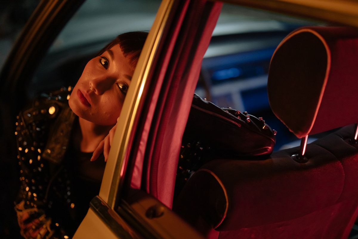 Close-up portrait of a woman in a car at night, creating a moody ambiance with play of light and shadows.