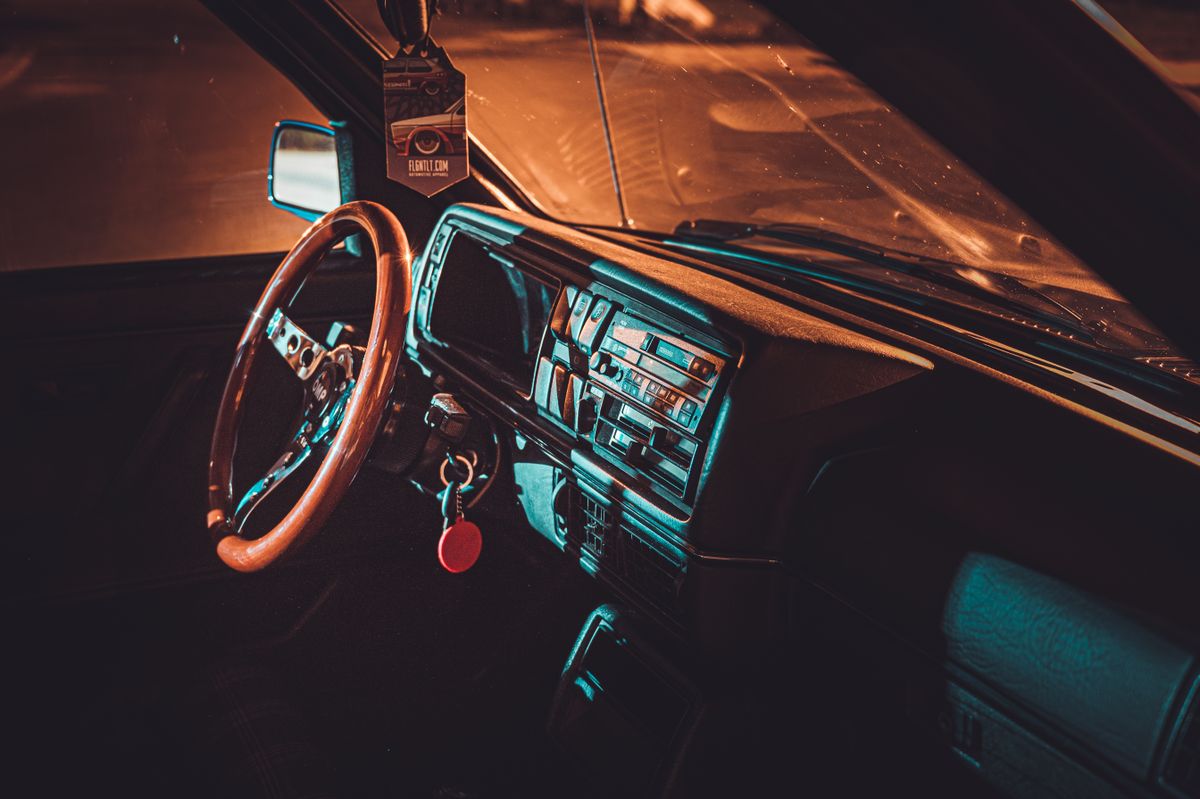 Explore the nostalgic elegance of a vintage car interior with wooden steering wheel in warm lighting.