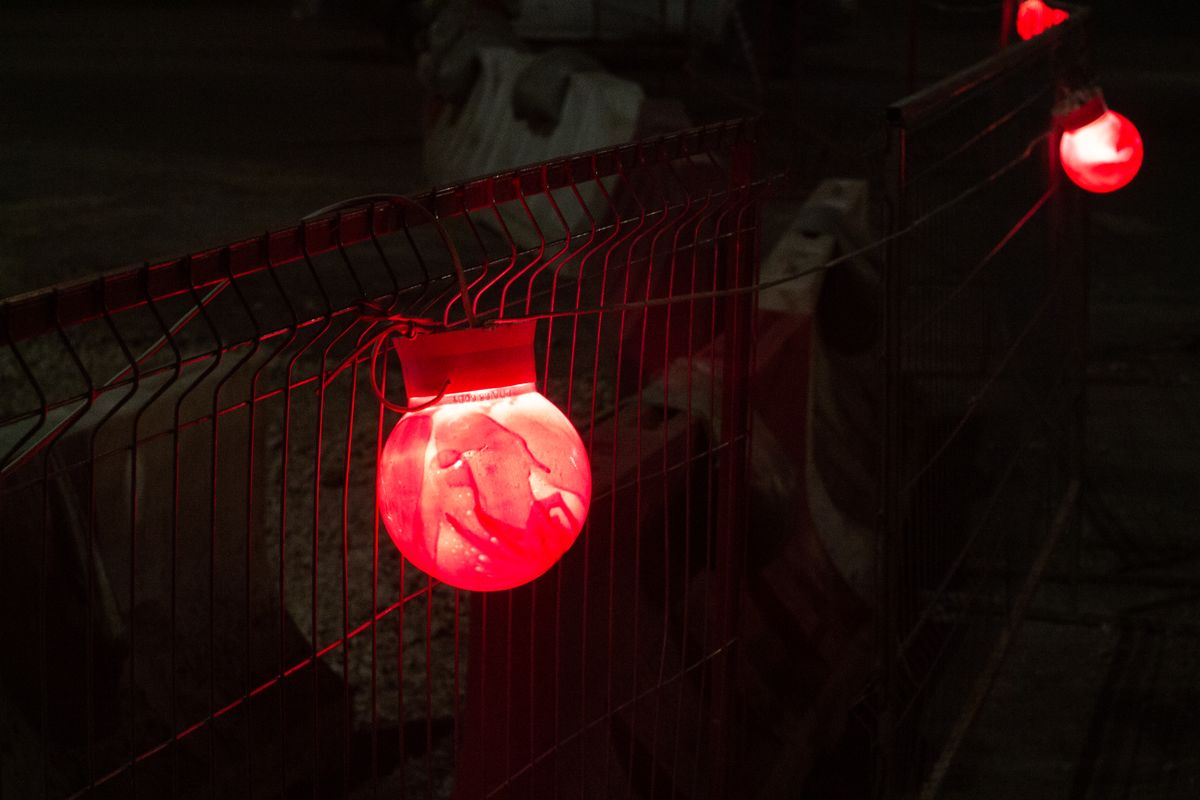 Close-up of red warning lights on a construction site fence at night, providing illumination and safety.