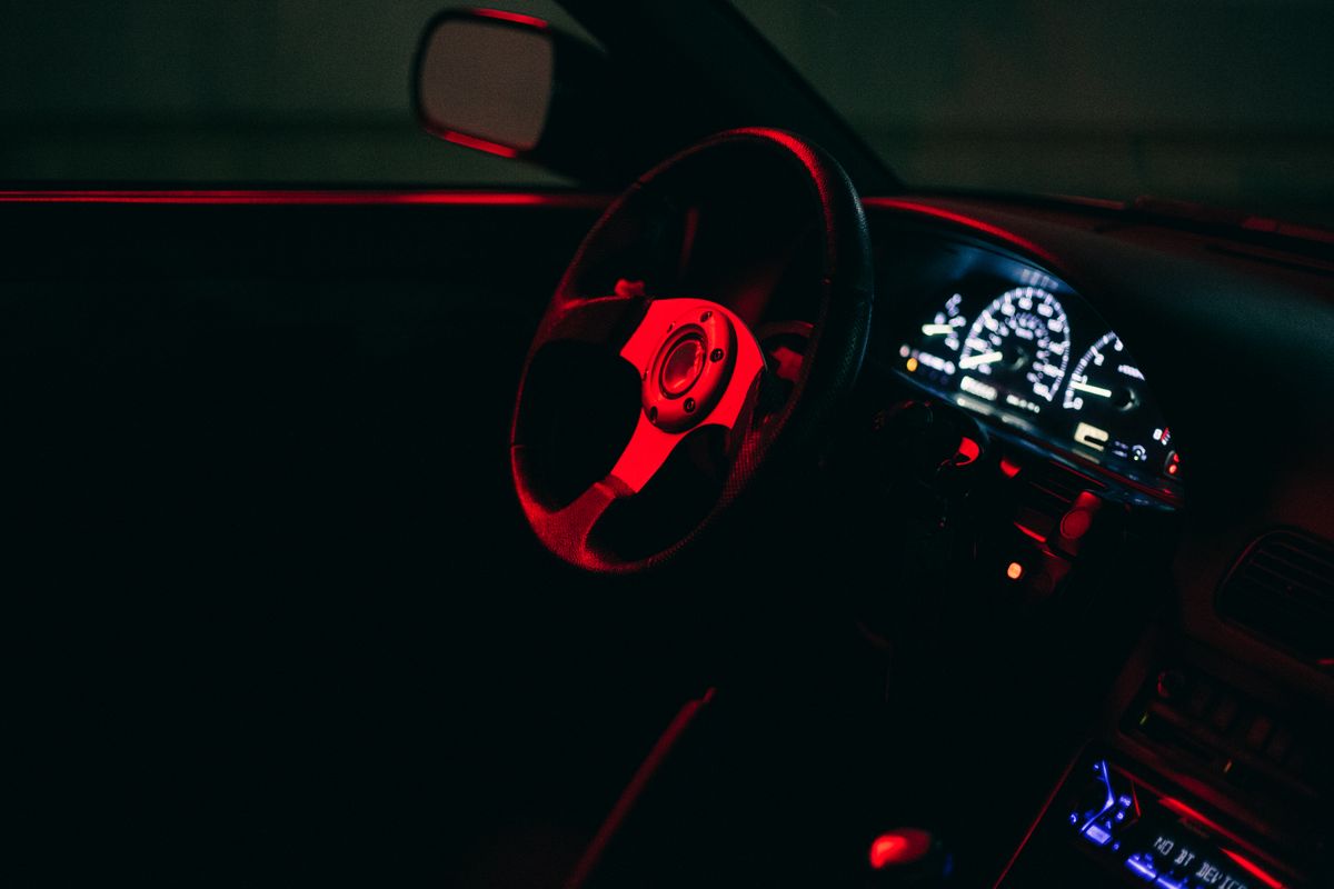 Stylish car dashboard illuminated by red lights, showcasing speedometer and modern design.