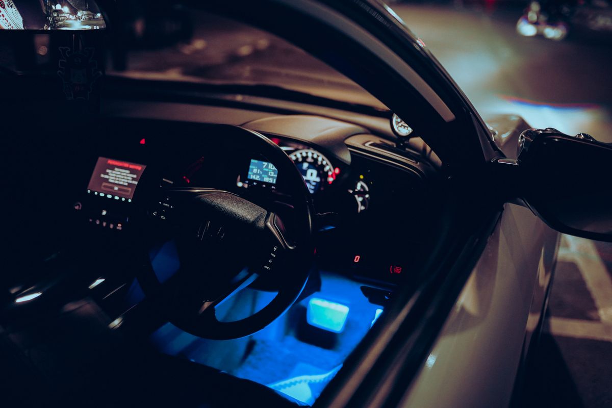 A luxurious car interior with an illuminated, modern dashboard shot from the driver's perspective at night.