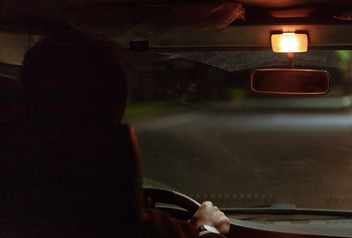 View of a car interior with a glowing dome light during nighttime driving.
