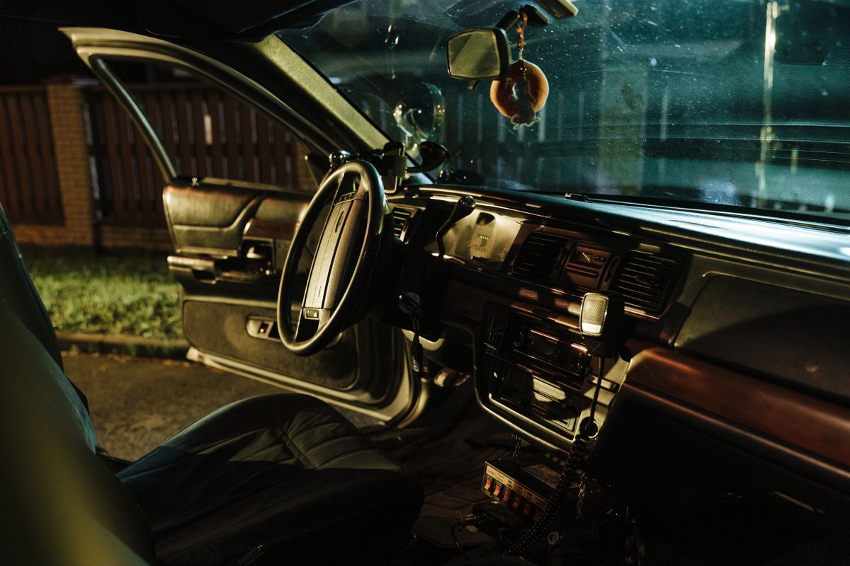 Stylish car interior shot at night with open door, highlighting steering wheel and seats.