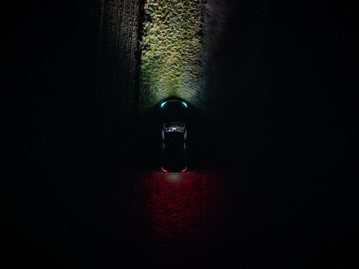 Drone captures a car on a dark road in Germany, highlighting vivid lights.