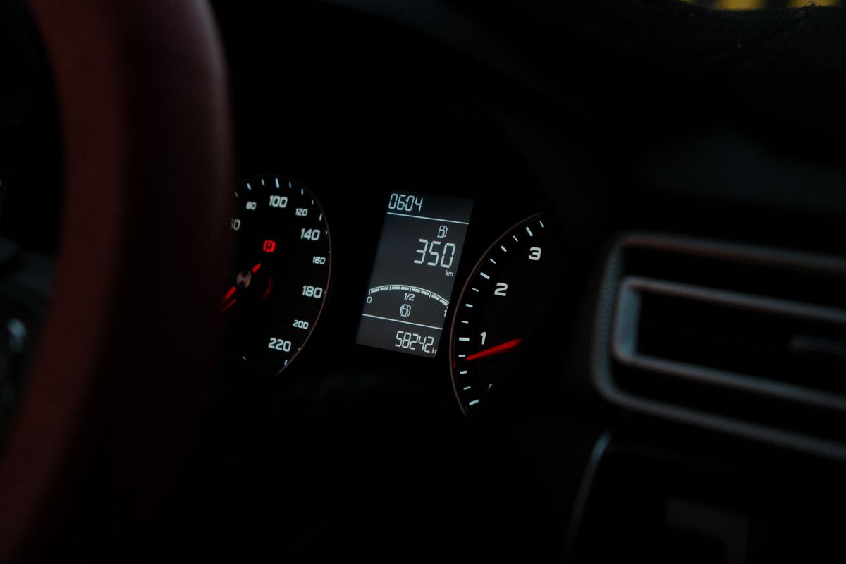Car dashboard showing speedometer and digital readout at night. Perfect for automotive or technology themes.