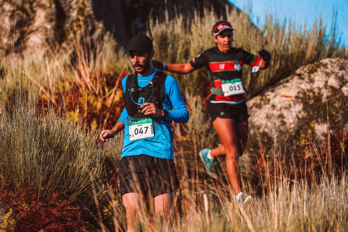 Two athletes running in a scenic outdoor trail marathon, showcasing endurance and fitness.