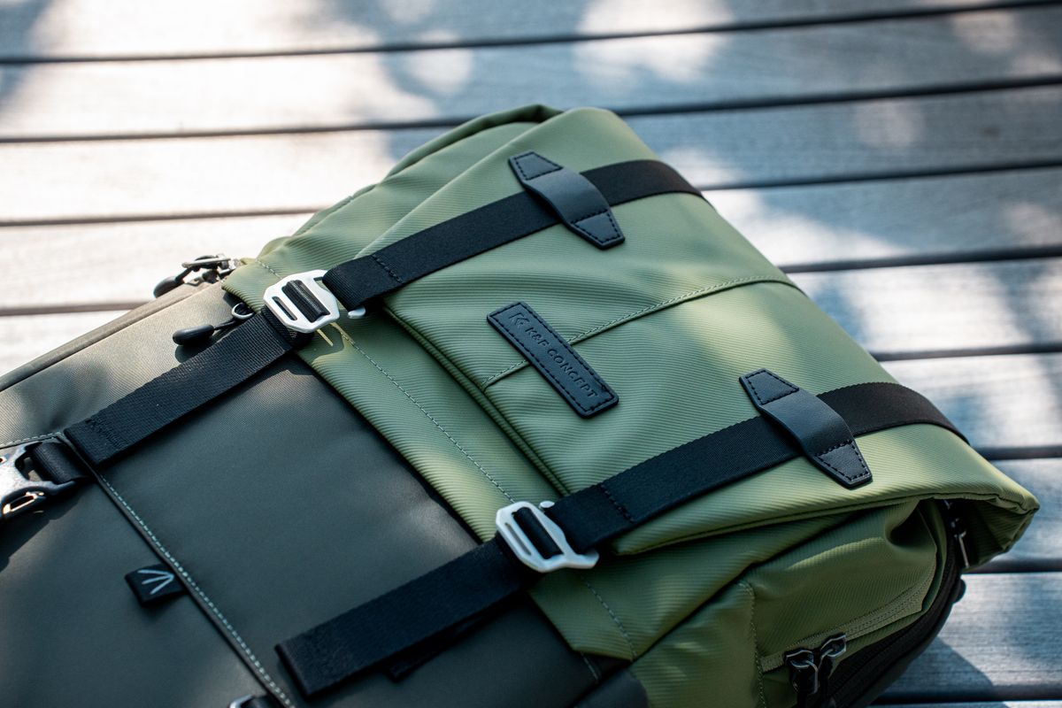 Close-up of a modern olive green backpack with black straps on a wooden surface, perfect for outdoor adventures.