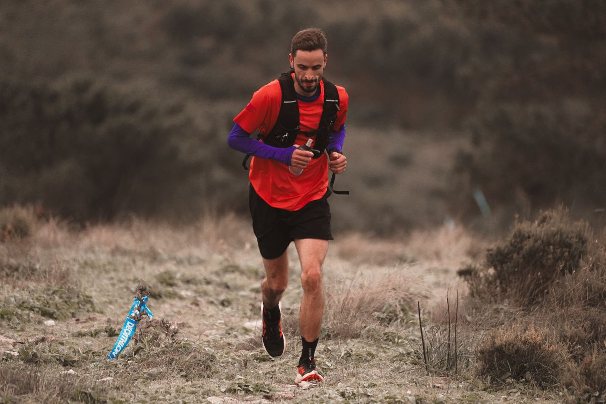 Man running in nature on a trail wearing vibrant red outfit. Outdoor fitness and endurance training.