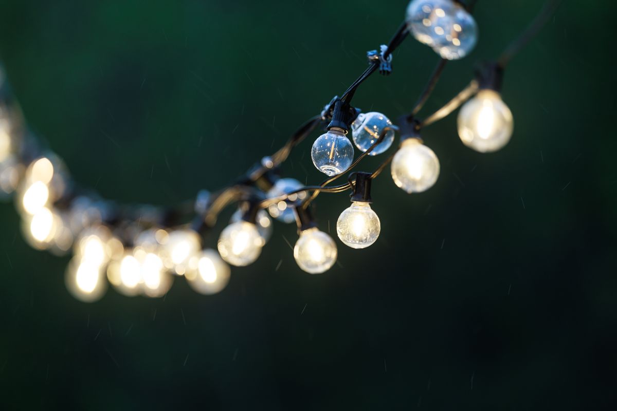 Aesthetic outdoor string lights glowing softly against a dark blurred background. Perfect for party and festive themes.