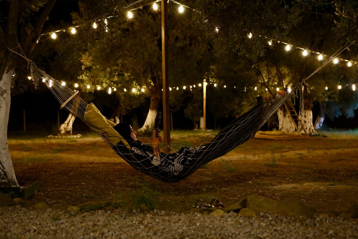 Relaxing in a hammock under glowing string lights at night in a peaceful environment.