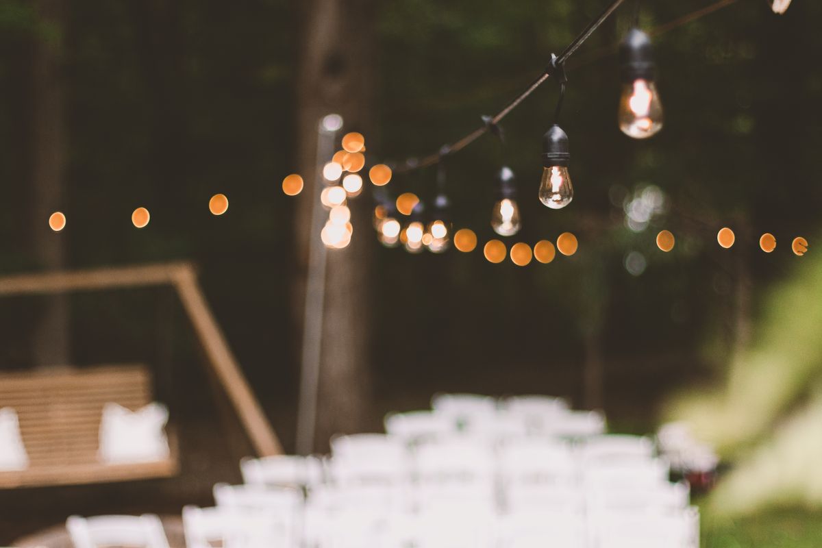 Warm and cozy string lights illuminating an outdoor garden setting at dusk, creating a festive ambiance.