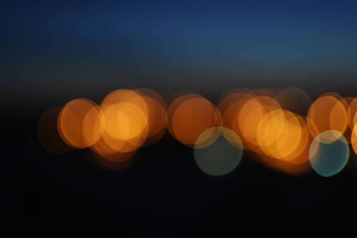 Blurred city lights form an abstract pattern against a dark night sky.