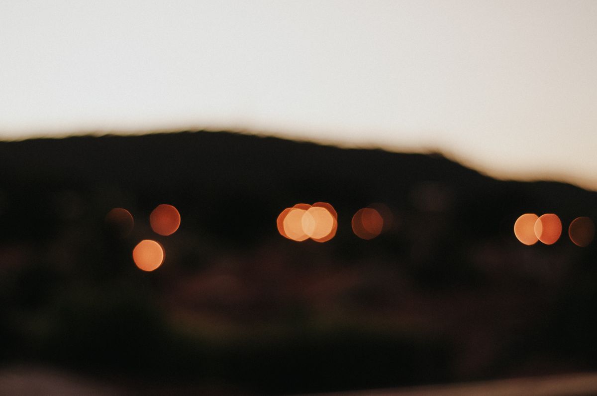 Blurred bokeh lights against a darkened landscape at twilight, capturing a serene outdoor ambiance.