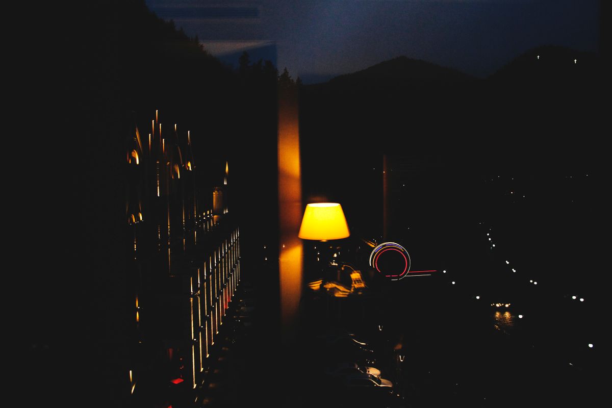 Warm bedroom light casting glow over city view, enhancing night ambience.