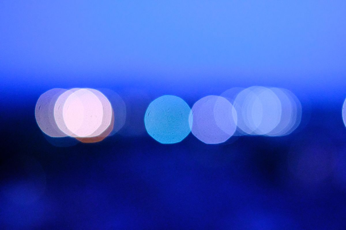 Blurry circular light patterns in blue create a serene abstract night background.